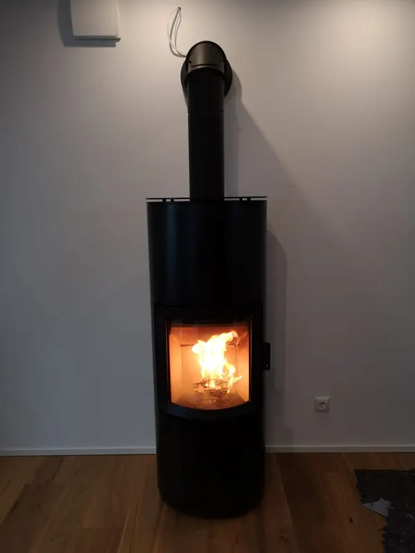 Schlanker schwarzer Kaminofen mit sichtbarem Feuer