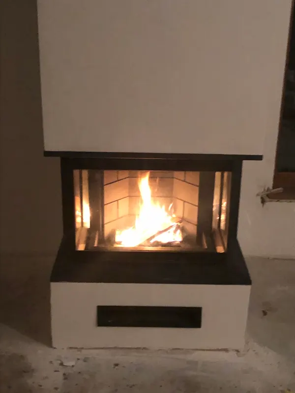Dreiseitig verglaster Kamin mit Feuer im Wohnraum
