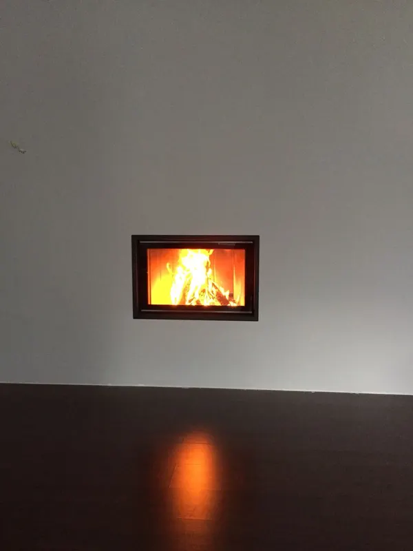 Frontkamin mit Flammen in einer hellen Wand